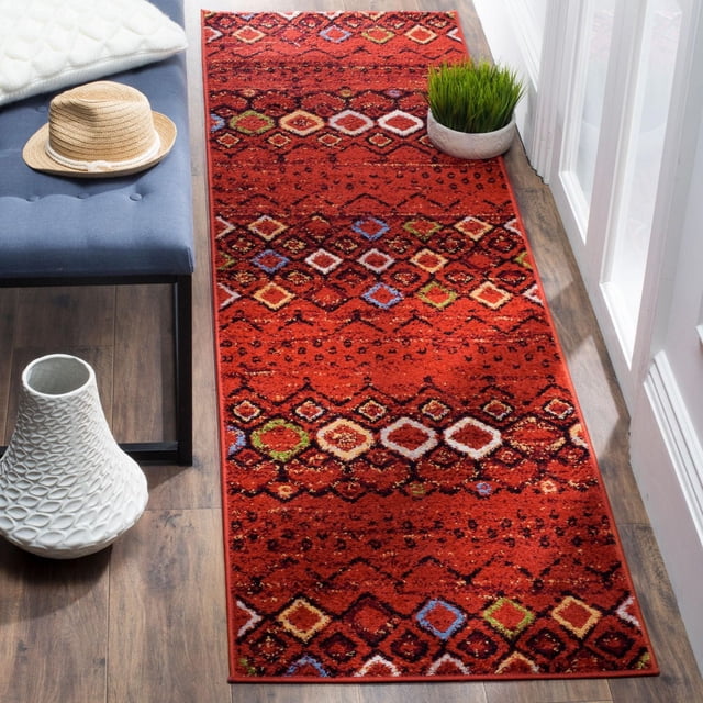 SAFAVIEH Amsterdam Gladwin Tapis Coureur Géométrique Présentant une base Ton Terre Rouge Riche avec des Motifs Tribaux Multicolores en Losanges en Bleu, Vert, Crème et Brun. Tissé Mécaniquement à Partir de Fils Synthétiques Durables, Il Est Placé sur un Plancher de Bois à Côté d'Un Banc Rembourré Bleu avec un Chapeau de Paille, un vase Texturé Blanc et une Plante en Pot Verte Près d'Une Porte en Verre. Convient pour Ajouter un style Rustique Chic aux Couloirs Ou Entrées Étroits.