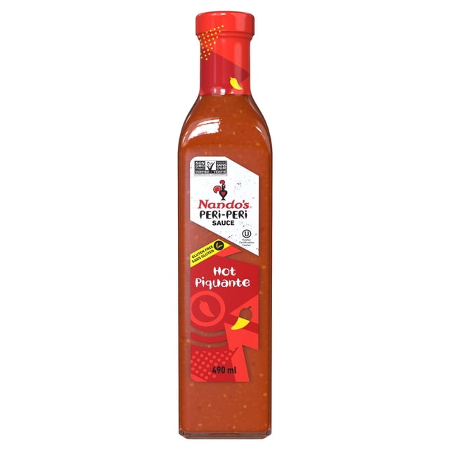 Nando's Hot Peri-Peri Hot Sauce in a 490ml clear glass bottle with a red cap and white label featuring the Nando's logo and gluten-free certification, containing a textured reddish-brown spicy condiment made with African Bird's Eye Chili, sun-ripened lemons, garlic, spices, and onions, ideal for adding heat to chicken, vegetables, and dips like hummus.