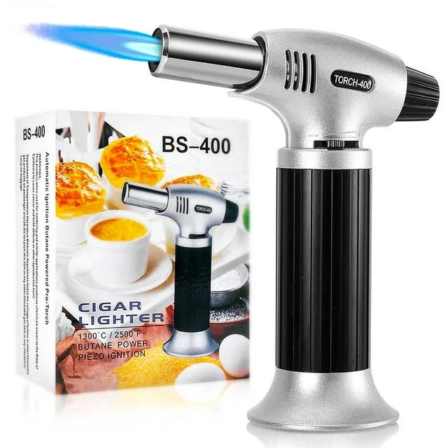 Culinary Butane Torch Lighters Kitchen Blow Torch for Cooking with Safety Lock & Adjustable Flame, shown in a silver and black design with a wide base for stability. The torch features a visible blue flame and a safety lock mechanism. Packaging in the background highlights its use for crème brûlée and other culinary applications. This refillable kitchen torch is made of durable aluminum alloy and includes a piezo ignition system for easy operation. Butane gas is not included.