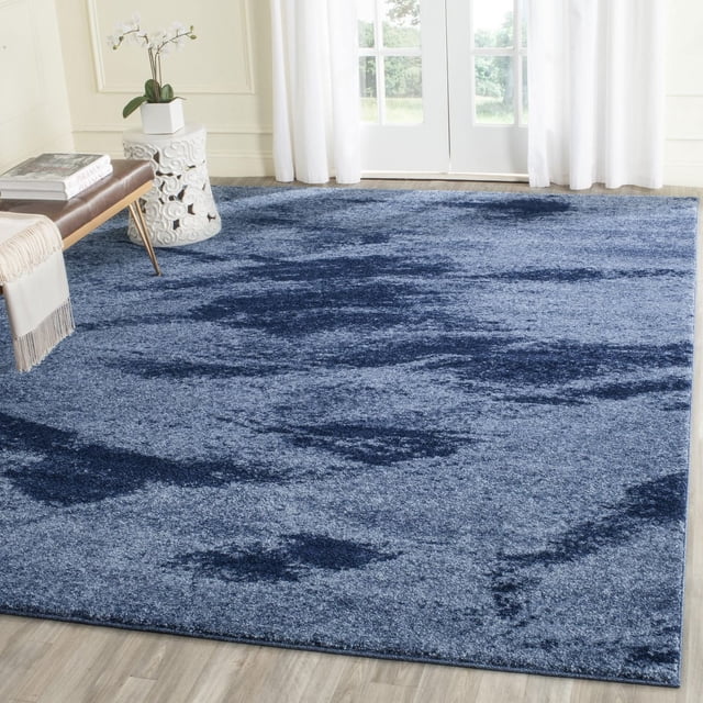 Safavieh Rétro Tapis Panit Abstrait pour Aire avec une surface en Polypropylène à Poil Ras dans des Tons Bleus Présentant un Motif Abstrait Moderne Mi-Siècle, Exposé sur un Plancher de Bois Clair dans une Pièce Lumineuse avec des Rideaux Blancs et un Mobilier Minimaliste, Idéal pour Accentuer les Intérieurs Contemporains.