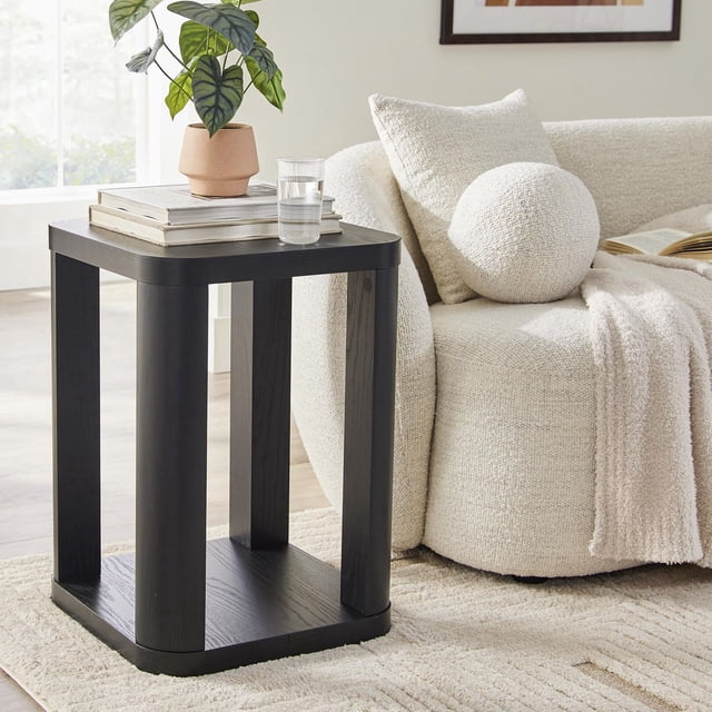 Better Homes & Gardens Table d'Appoint Juliet en Ton Bois Noir avec Bords Arrondis et Tablette Inférieure Ouverte, Montrée à Côté d'Un sofa en Bouclé Crème avec Coussins et un Jeté, Tenant une Plante en Pot en Terre Cuite, des Livres Empilés et un Verre d'Eau dans un Salon Lumineux, Convient Aussi comme Table d'Appoint de patio Ou Table d'Accent.