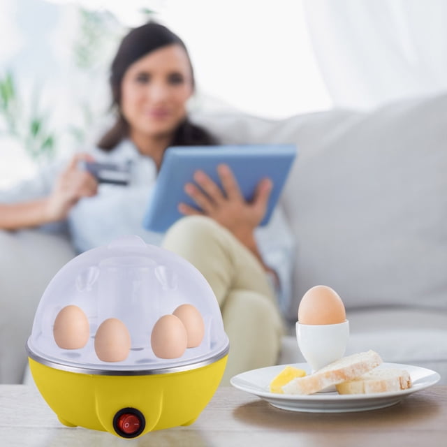 Electric food steamer for cooking with a yellow base and transparent dome lid, shown steaming five eggs. The compact design is ideal for steaming vegetables, dumplings, seafood, and more. Rated at 350W with a 7-egg capacity, it is easy to use and clean. The steamer is displayed on a table in a cozy living room setting with a person in the background holding a tablet.