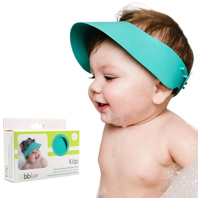 bblüv - Käp - Silicone Shampoo Repellent Cap in teal on a baby’s head from side profile, made of soft, flexible silicone with adjustable strap, shown next to its white and green packaging box featuring product image and branding, designed to protect baby's eyes and ears from water and shampoo during bath time.