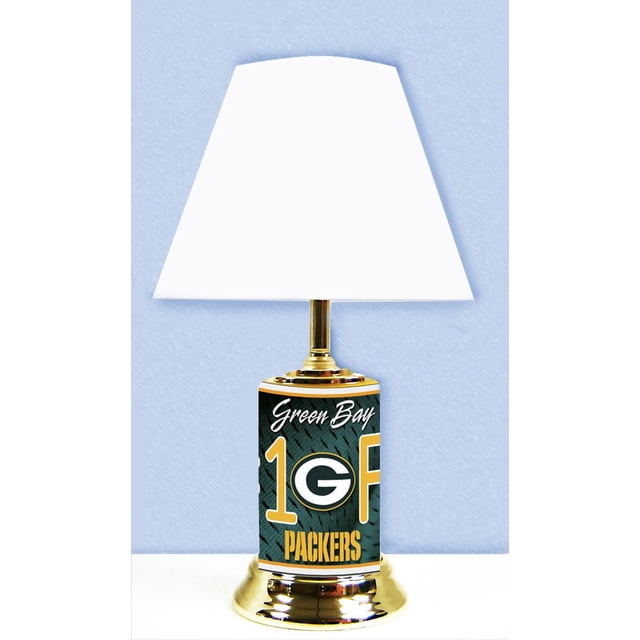 NFL Green Bay Packers Table Lamp with a white tapered lampshade and a cylindrical base displaying official team graphics including the Green Bay Packers logo and 'Green Bay 1 Fan Packers' text in green, gold, and white, set on a polished gold-tone metal base, suitable for fan caves, offices, or bedrooms.