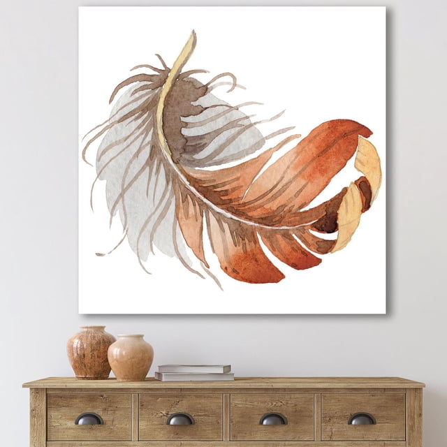 Designart Orange Ethnic Bird Feather Canvas Wall Art depicting a watercolor feather in orange, brown, and beige on white gallery-wrapped cotton canvas, ready to hang, displayed above a wooden console table with decorative vases and books, suitable for bohemian and eclectic home décor.
