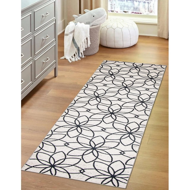 ECARPET Washable Floral Area Rug & Runner for Bedroom, Living Room, Kids Room, Hallway with a low pile polyester base featuring a black floral pattern on white, set on light wood flooring near a white pouf and a basket with a plush shark and fringed throw, ideal for high traffic indoor spaces.