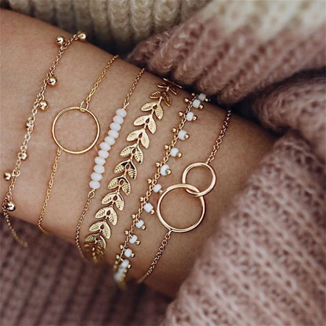 TopLLC Bracelets Mode Femmes Acier Inoxydable Lots Style Manchette Ouverte Bracelet Jonc Chaîne Bracelet. une Vue Gros Plan de Bracelets Ton or Portés au Poignet, avec des motifs Ajustables avec des Feuilles, des Perles Blanches, des Cercles Emboîtables et des Pompons. Faits d'Acier Inoxydable, de Cristal, de Pierre Naturelle et de Perles, Ces Bracelets Sont Idéals pour Offrir Ou Accessoiriser Toute Tenue.