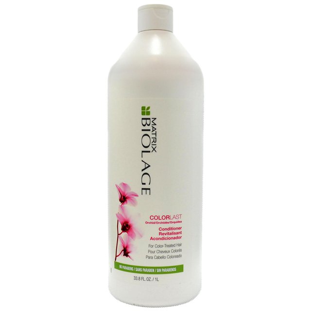 Matrix Biolage Colorlast Revitalisant, Orchidée (33,8 fl oz) dans une Grande Bouteille Blanche avec Bouchon à Rabat. l'Étiquette Présente des Graphiques d'Orchidée Rose et un Texte Mettant en Valeur Sa Formule Sans Parabènes pour Préserver des Cheveux aux Couleurs Vibrantes pendant jusqu'à 9 Semaines.