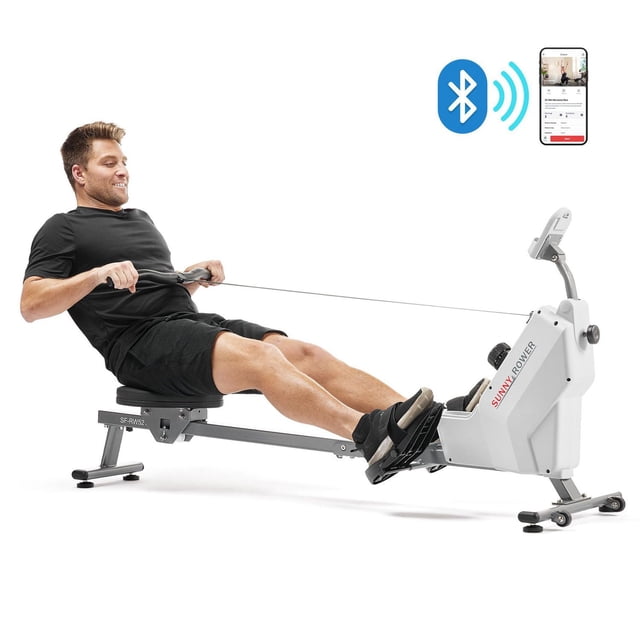 Sunny Health & Fitness Smart Compact Magnetic Rowing Machine with Exclusive SunnyFit® App Enhanced Bluetooth Connectivity – SF-RW521020 in grey, shown with a user rowing, featuring an 8-level magnetic resistance system, cushioned seat, anti-slip foot pedals, foldable frame for easy storage, and a digital monitor displaying workout metrics, ideal for low-impact indoor cardio and fitness tracking via Bluetooth app.