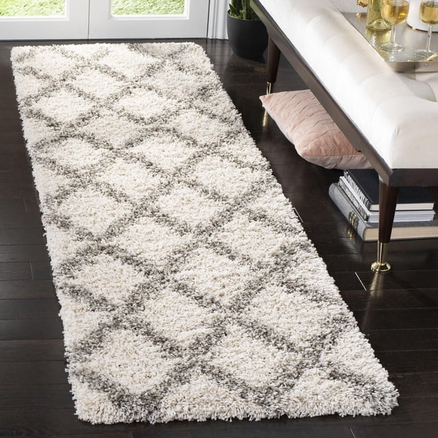 Safavieh Hudson Franklin Tapis Shag à Losanges Géométriques Mettant en Vedette une Peluche Shag Ivoire avec des Motifs de Carreaux à Losanges Gris, Exposé comme un Coureur sur un Plancher de Bois Franc Foncé à Côté d'Un Banc Rembourré Blanc avec des Pattes à Pointe Dorée, Convient pour Ajouter de la texture aux Espaces de Vie Modernes.