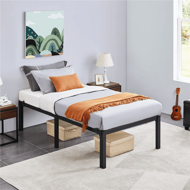 Yaheetech Metal Platform Bed Frame with Steel Slat Support, Twin, Black, featured in a modern bedroom. The durable steel frame with sturdy metal legs and slats provides stability for latex, memory foam, or spring mattresses. The 16.5-inch under-bed storage space is ideal for organizing quilts, pillows, or seasonal items. Reinforced corner brackets and anti-slip baffles ensure noise-free and secure mattress placement. Reserved holes on the legs allow for headboard attachment, offering customization options. The matte black finish complements the room's decor, including grey and orange bedding, wooden side tables, and wall art. Perfect for bedroom furniture needs.