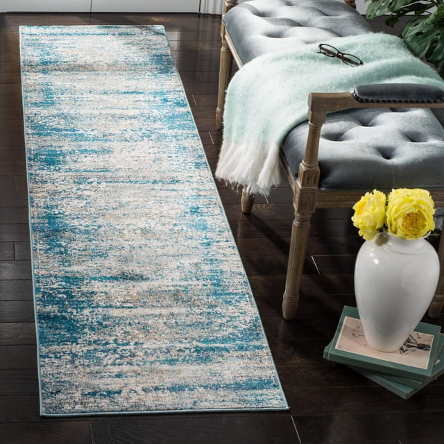 Safavieh Aria Tapis Coureur Bohème Abstrait Rubye avec un Motif Abstrait Usé dans des Tons Sarcelle et beige, Fils Synthétiques Tissés Mécaniquement pour la Durabilité, Placé sur un Plancher de Bois Franc Foncé à Côté d'Un Banc Capitonné Gris avec des Pattes en Bois, un Jeté Vert Doux et un vase Blanc avec des Fleurs Jaunes sur des Livres Empilés, Idéal pour les Zones à Fort Passage.