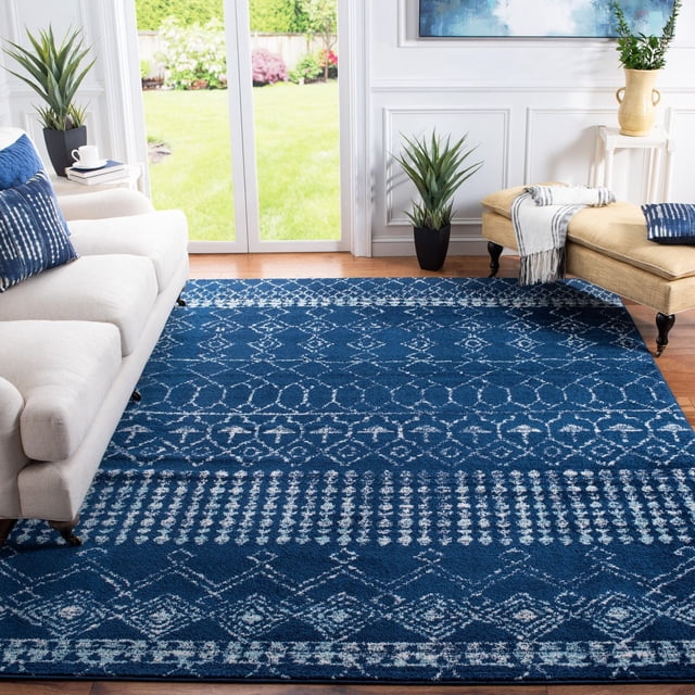 Safavieh Tapis Géométrique Marocain Tulum Coriandre Bleu Foncé avec Motifs Géométriques Blancs, texture Laine Nouée à la Main, Posé sur Planchers de Bois Franc dans un Salon Lumineux avec sofa beige, Banc beige et Plantes Vertes Près de Portes Coulissantes en Verre, Convient pour Ajouter de la Chaleur aux Espaces Contemporains.