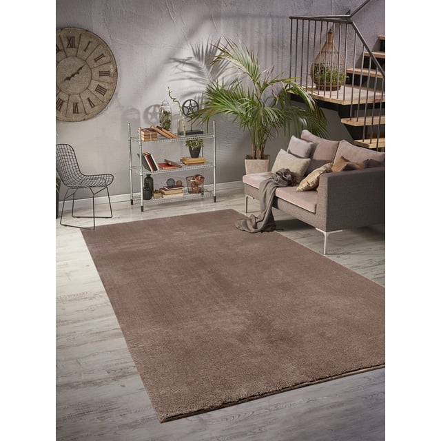 LaDole Rugs 3x10 ft Fluffy Shaggy Area Runner Rug in taupe, featured in a contemporary living room with a grey sofa, decorative pillows, and a metal shelving unit. The rug's high-pile texture provides a soft, luxurious feel, making it suitable for hallways, kitchens, and entryways. It is machine washable and shown on a light wood floor, blending seamlessly with the neutral decor.