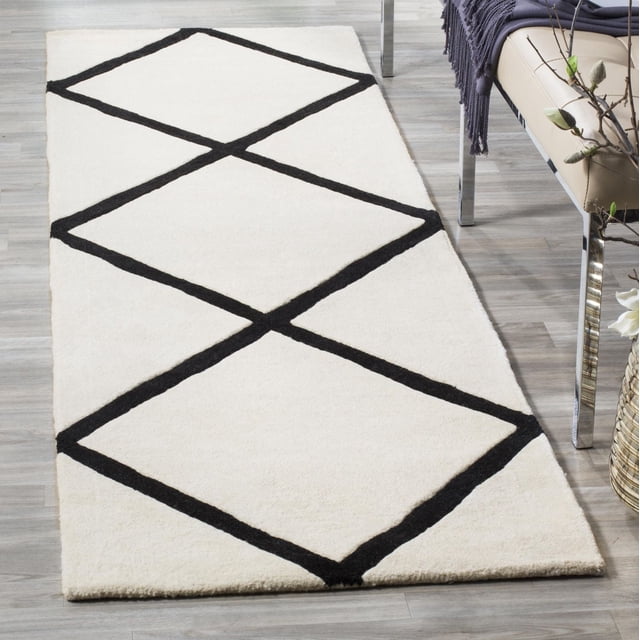 Safavieh Chatham Isaac Tapis à Losanges Géométriques Exposé sur un Plancher de Bois Franc Clair, Présentant une texture de Laine Tuftée à la Main avec une base Crème et un Motif de Losanges Géométriques Noir, Placé à Côté d'Un Banc beige avec des Pattes Chromées et un Jeté Foncé, Convient pour Rehausser des Intérieurs Contemporains.
