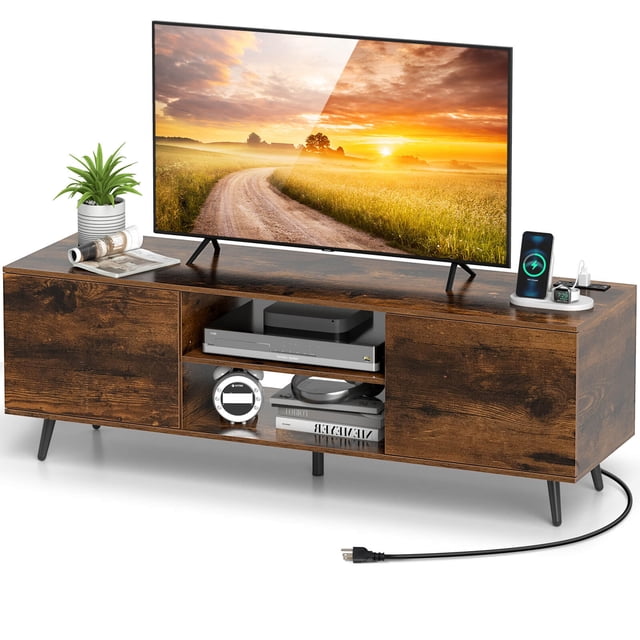 Costway Meuble Télé pour Téléviseurs de 60 Pouces au design Moderne Mi-Siècle, Doté d'Une Finition Brun Rustique. le Meuble Comprend un Grand Plateau Supportant des Téléviseurs jusqu'à 60 Pouces, Deux Étagères Ouvertes et Deux Armoires avec Portes pour le Rangement. des Prises de Courant Intégrées et des ports USB Sont Visibles pour un Chargement Pratique de l'Appareil. l'Unité Est Surélevée sur Cinq Pieds Métalliques Robustes avec Patins Antidérapants, Offrant une Stabilité et un Nettoyage Facile en Dessous. un Trou de Gestion des Câbles Est Présent pour une Organisation Ordonnée. la console