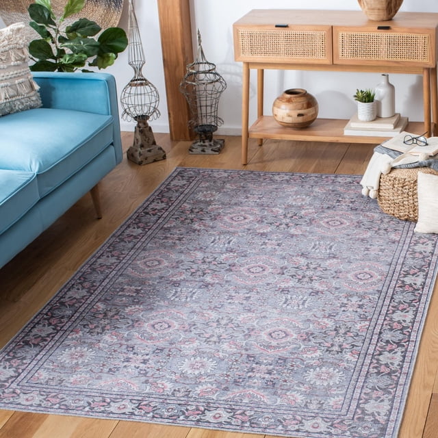 SAFAVIEH Serapi Amable Oriental Area Rug featuring a traditional floral medallion pattern in muted grey and pink tones with a distressed patina, power loomed from cotton, viscose, and polyester fibers, displayed on light hardwood flooring in a living room with a blue sofa and a wooden console table with woven drawer fronts, ideal for adding comfort and classic style to home interiors.