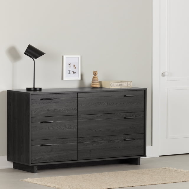 South Shore Fynn 6-Drawer Dresser for Child in gray oak finish with six drawers and black metal handles, featuring smooth metal slides for quiet access, placed in a minimalist room with a black desk lamp, framed animal art, wooden bear stacking toy, and Scrabble game on top, ideal for organized kids' room storage.