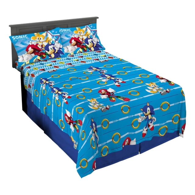 Sonic "Speed Freak" Full Sheet Set on a full-size bed with bright blue microfiber fitted and flat sheets featuring Sonic, Tails, and Knuckles characters alongside gold rings and arrow patterns, plus two matching pillowcases with Sonic and Tails on a blue background, suitable for kids' bedrooms.