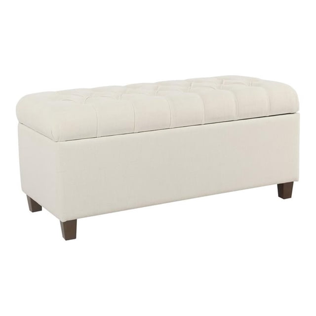 HomePop Ainsley Traditional Fabric Button Tufted Storage Bench in Cream. This rectangular bench features a soft cream woven polyester fabric with button tufting on the hinged lid, providing both style and functionality. The bench includes solid wood legs in a contrasting dark finish and offers spacious internal storage for pillows, blankets, or other items. Dimensions are 18 inches high, 40 inches wide, and 18 inches deep, with a weight capacity of 250 lbs. Suitable for use in entryways, living rooms, or bedrooms.