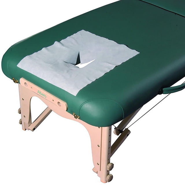 Master Massage Disposable Breathing Space Cover (Pack of 100) for Massage Table placed on a green massage table with beige wooden legs, made of soft, thick white non-woven fabric with a universal cross hatch opening for the face port, ideal for sanitary use in spas, clinics, tattoo shops, and home massage.