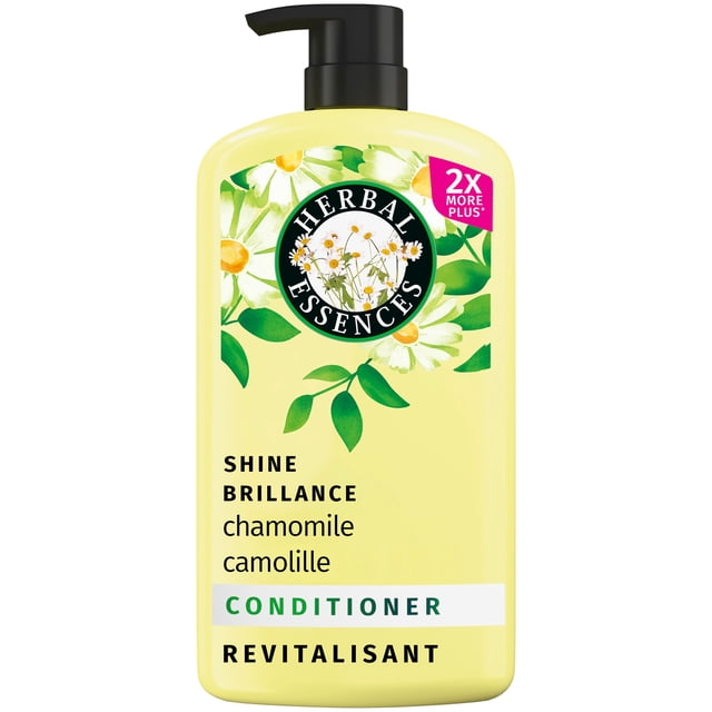 HERBAL ESSENCES SHINE CHAMOMILE CONDITIONER 1L in a yellow bottle with black pump dispenser, featuring chamomile flower graphics and bilingual English-French text. This color-safe, cruelty-free conditioner gently adds shine and smoothness to hair while maintaining pH balance.