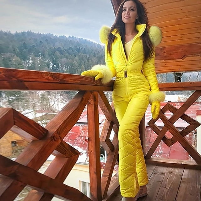 Pisexur Combinaison de Neige une Pièce pour Femme, Combinaisons de Ski de Couleur Jaune Vif, Conçue pour les Activités Extérieures d'Hiver comme le Ski et le Planche à Neige. la Combinaison Présente une Coupe Ajustée, une Taille Haute avec Fermeture Éclair et Boutons-Pression pour une double protection. Elle Comprend une Capuche, des Poignets Ajustables et une Taille Ceinturée pour un Ajustement Sécuritaire. le Tissu Imperméable et Coupe-Vent Assure Chaleur et Confort par Temps Froid. le Modèle Se Tient sur un Balcon en Bois avec un Paysage de Montagne Enneigée en Arrière-Plan.