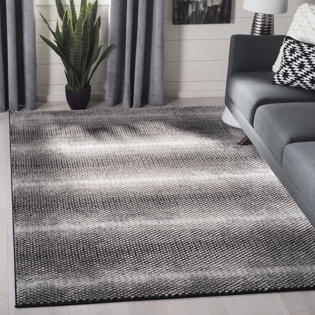SAFAVIEH Lurex Wilson Tapis Géométrique Abstrait Présentant un Poil Surélevé Texturé Noir et Blanc avec des Motifs Géométriques Organiques, Posé sur un Plancher de Bois Franc Clair dans un Salon avec un sofa Gris, des Coussins à Motifs et une Plante Serpent en Pot.