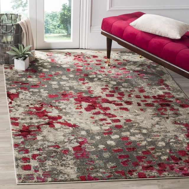 Safavieh Monaco Driskoll Abstract Area Rug featuring a durable power-loomed polypropylene construction with mixed high and low loop pile in an abstract pattern of red, beige, and gray, displayed on a light wood floor beside a red tufted bench with a white cushion and a wicker basket with a plant near a glass door, ideal for adding Bohemian-chic flair to home décor.