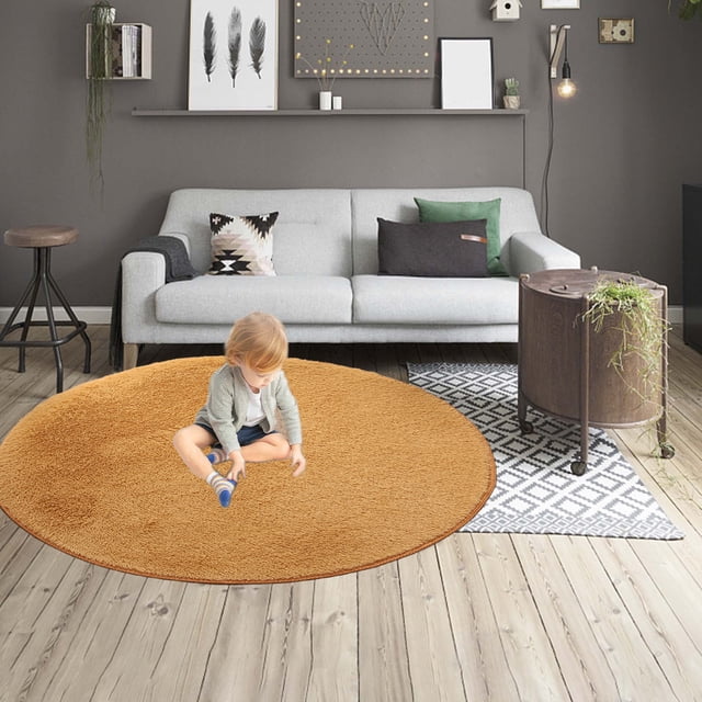 40 Inch Round Non-Shedding Short Pile Rug for Living Room Bedroom, shown in a modern living room setting with a light grey sofa, decorative pillows, and a wooden coffee table. The rug is yellow, round, and features a low pile with a rubber backing for non-slip functionality. Suitable for high-traffic areas and easy to clean.