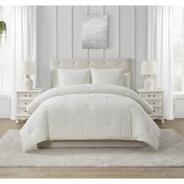 Springmaid Ensemble de Douillette Rowan à Médaillon Présentant un Motif de Médaillon Texturé Blanc sur la Douillette et des Couvre-Oreillers Assortis, Affiché sur un Lit Capitonné beige Rembourré avec des Tables de Nuit Blanches et des Lampes dans une Chambre Éclatante avec des Murs à Panneaux Blancs et des Rideaux Transparents. l'Ensemble de Douillette Lavable à la machine Est Offert en Formats Double/Grand et Très Grand et Est Souvent Utilisé pour Ajouter une Couche Douillette et Stylée à la Déco de Chambre.