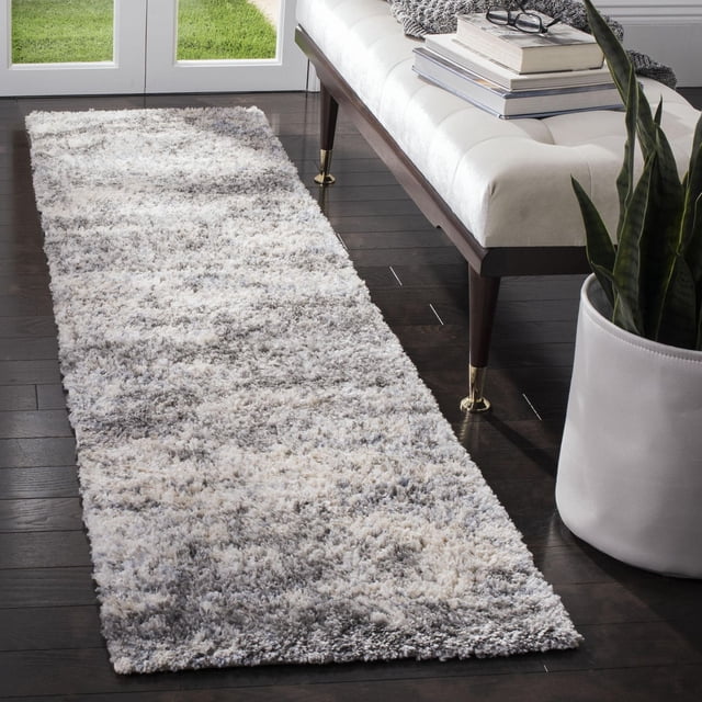 SAFAVIEH Berber Harold plush shag area rug with abstract gray and white pattern placed on dark hardwood floor next to a modern bench and potted plant