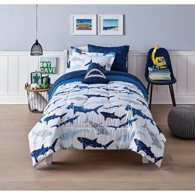 Mainstays Kids Bed in Ensemble de Literie « a Bag » pour Lit Simple avec Couette Blanche Imprimée de Requins Bleus et Gris, Draps en Microfibre Bleu Foncé, Taies d'Oreiller Coordonnées et Coussin Décoratif en Forme de Requin dans une Lumière, Chambre d'Enfant à Thème Côtier avec Plancher de Bois et photos Encadrées d'Océan.