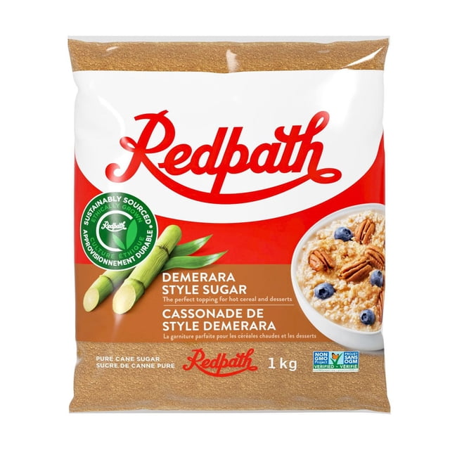 Redpath Demerara Style Sugar 1 kg bag showing large golden brown sugar crystals through clear packaging with the Redpath logo, sugar cane illustration, and oatmeal bowl with pecans and blueberries, suitable for baking, hot cereal, and dessert toppings, sustainably sourced, kosher certified, gluten free, non-GMO, and vegan friendly.