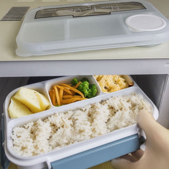 EGNMCR Kitchen Gadgets, Kitchen Accessories 4 Compartments In One Large Lunch Box Leakproof Lunch Box. A gray plastic lunch box with four compartments, filled with rice, broccoli, carrots, and crackers, being placed into a microwave. The lid features a sealed design with a circular vent for steam release. Made of food-grade material and microwave-safe, ideal for dining out, work, or school.