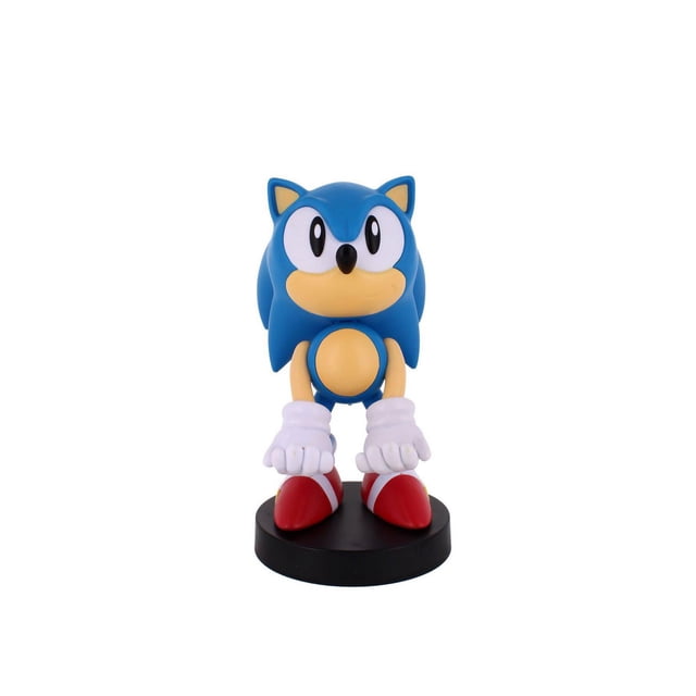 Exquisite Gaming Sonic Cable Guy Original Controller and Phone Holder with a front-facing blue Sonic figure featuring beige muzzle and belly, large white eyes, white gloves, and red shoes standing on a black circular base, compatible with PlayStation, Xbox, Switch controllers and most phones, often used to hold TV remotes.