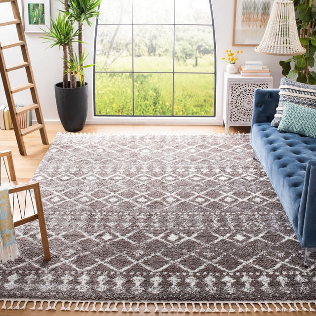 Safavieh Berber Fringe Robynne Tapis Shag Aztèque pour Salon Ensoleillé avec Grande Fenêtre Montrant de la Verdure, Présentant une Peluche de 1,25 Po avec des Motifs Tribaux Aztèques Blancs sur des Bords Gris et à Franges, Assorti à un sofa Capitonné Bleu, une Échelle en Bois, une Plante en Pot et une table d'Appoint Décorative avec Livres et Lampe, Idéal pour Ajouter un style Bohème et du Confort aux Espaces de Tapis d'Accent.