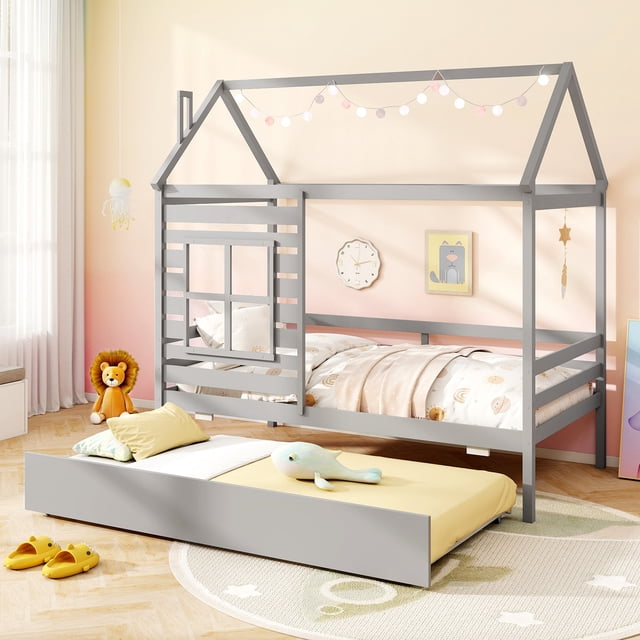 Gymax Lit Cabane Format Simple avec Tiroir-Lit, Lit Plateforme en Bois Gris avec Cadre en Forme de Maison avec Toit, Cheminée et Fenêtre Décorative. le Lit Comprend un Tiroir-Lit Qui Se Déplie en Douceur, Idéal pour les Soirées Pyjama. Fabriqué en Bois Massif et Lattes en Contreplaqué, Offre un Soutien Robuste Sans Besoin de Sommier. le Lit Est Présenté dans une Chambre d'Enfant Douillette avec Décor pastel, Guirlandes Lumineuses et Jouets en Peluche, Mettant en Valeur Son design Fantaisiste.
