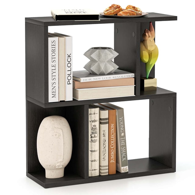 Costway 1 PCS 3-Tier Bookshelf Geometric Bookcase Side Table with Open Storage Display Shelf Black. A compact black engineered wood bookshelf featuring a unique geometric design with three open tiers. The top shelf holds books, a decorative sculpture, and pastries, while the middle and bottom shelves display books, a vase, and ornaments. Non-slip foot pads enhance stability, and screw hole stickers provide a clean finish. Ideal for living rooms, bedrooms, or study rooms.
