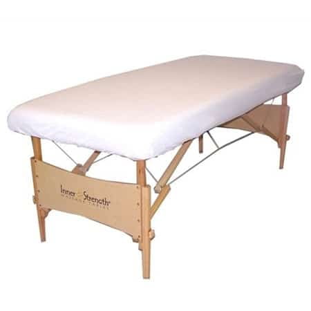Massage Bed Fitted Sheets - Standard Percale (6 Pack) 39x80x9" White shown on a wooden massage table. The fitted sheet features a smooth, breathable fabric with a 180 thread count and 50/50 cotton-polyester blend, designed for massage therapy and spa use. Lightweight and durable, ideal for warmer climates and frequent washing.