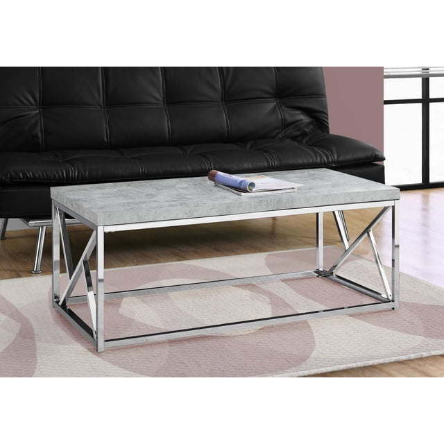 Monarch Specialties Coffee Table with a rectangular grey cement-look laminate top and chrome metal criss-cross base, placed on a patterned rug in front of a black leather sofa, ideal for living rooms, dens, or office spaces.