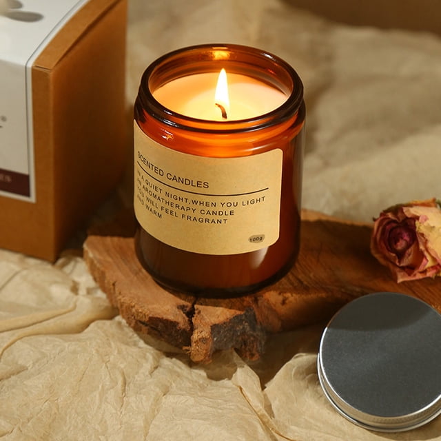 Dvkptbk scented candle for home with strong fragrance, crafted from soy wax, presented in a brown glass jar with a minimalist label. The lit candle emits a warm glow, placed on a rustic wooden surface with a metal lid and dried rose nearby. Suitable for aromatherapy, home decor, or as a thoughtful gift.