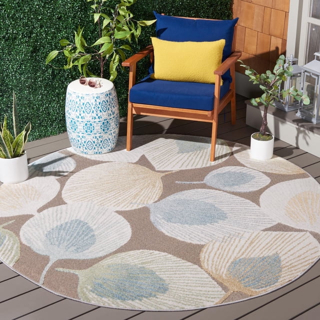 SAFAVIEH Sarasota Nash Tapis d'Intérieur/extérieur à Motif Floral, Rond avec de Grands Motifs Floraux en Bleu, beige et Vert Atténués sur taupe, Posé sur une Terrasse en Bois avec une Chaise en Bois Rembourrée Bleue, un Coussin Jaune, des Plantes en Pot et une table d'Appoint Décorative en Céramique, Convient à l'Intérieur et à l'Extérieur.