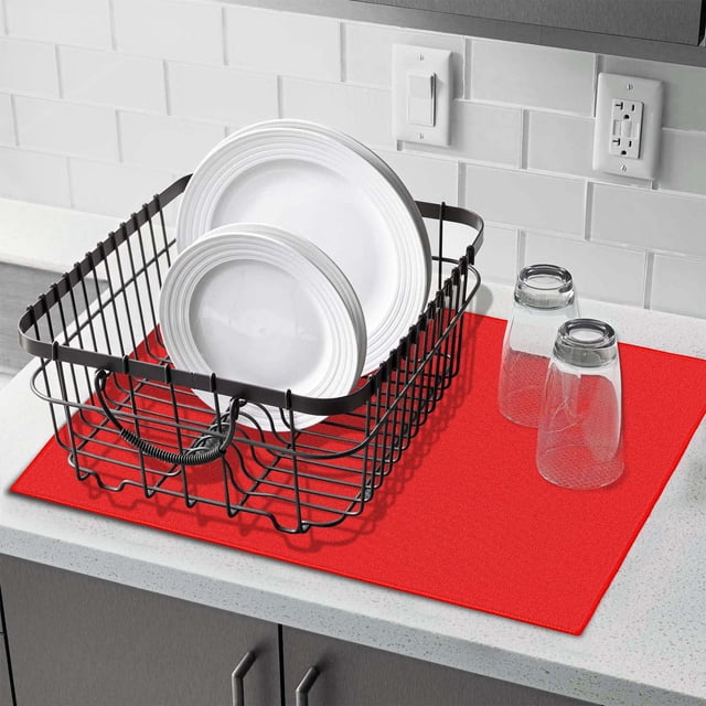 Fabstyles Tapis d'Égouttage pour Vaisselle en Microfibre Rouge, Placé sur un Comptoir de Cuisine Blanc avec un Égouttoir en Fil Métallique Noir Tenant des Assiettes Blanches et Deux Verres Transparents Inversés à Côté, Soutenu par un Dosseret en Carreaux de Métro Blanc avec Prises Électriques, Idéal pour un Séchage Rapide et Efficace de la Vaisselle et de la Verrerie.