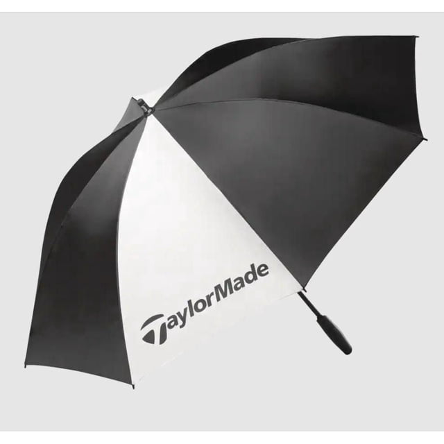 TaylorMade Umbrella with a 60-inch nylon canopy in alternating black and white panels, lightweight aircraft aluminum shaft, and ergonomic rubber-coated sport-grip handle, featuring bold TaylorMade branding on the white panel, suitable for golf weather protection.