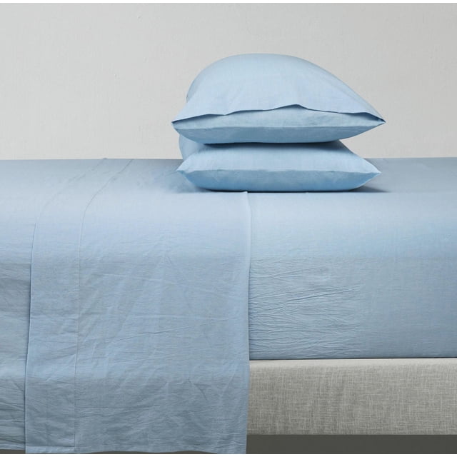 Cotton Solid Prewashed sheet Set in light blue on a bed with two matching pillowcases stacked, made from breathable 100% cotton with natural wrinkles and a fitted sheet that fits mattresses up to 14 inches deep, ideal for refreshing bedroom bedding and suitable for guest rooms.