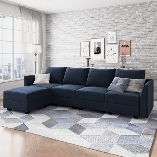 HONBAY Canapé en Velours en Forme de L avec Méridienne Réversible et Pouf de Rangement pour Salon, Bleu Marine. Ce Sofa Sectionnel Présente un Tissu en Velours Doux à l'Éclat Luxueux, Offrant Confort et Durabilité. la Méridienne Réversible et le Pouf de Rangement Offrent Flexibilité et Fonctionnalité, avec des Compartiments pour Ranger des Livres, des Appareils Électroniques Ou d'Autres Articles. Exposé dans un Salon Contemporain avec un Mur de Briques Gris Pâle, une Oeuvre Encadrée et un Tapis à Motif Géométrique.