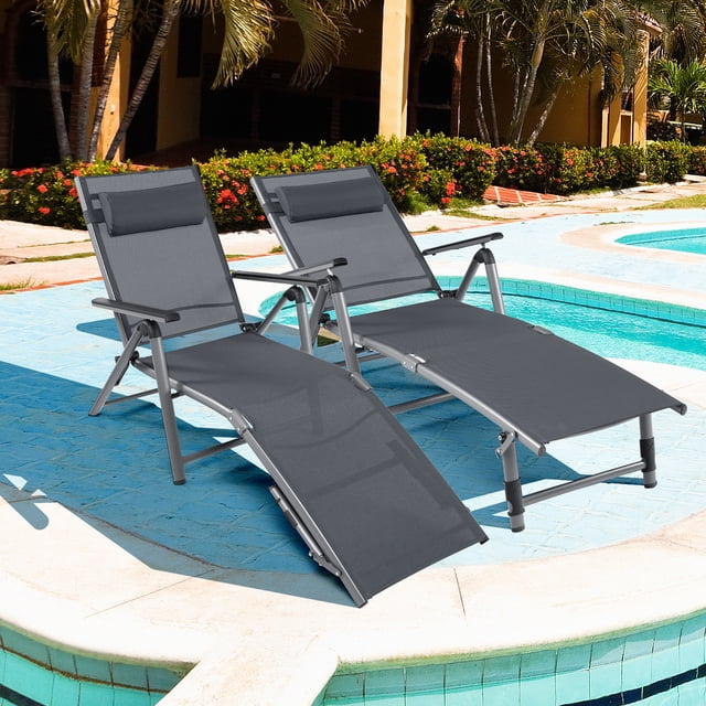 Costway 2PCS Patio Folding Aluminum Lounge Chair Chaise Adjustable Back Armrest Headrest shown in a poolside setting. The set includes two black chaise lounge chairs with breathable, quick-drying fabric and adjustable headrests. Each chair features an 8-position adjustable backrest and 2 leg positions for customized comfort. The lightweight aluminum frame is rustproof and foldable for easy storage and portability. Ideal for outdoor relaxation, reading, or sunbathing.