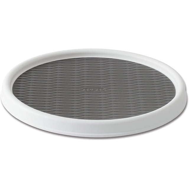 Non-Skid Pantry Cabinet Lazy Susan Turntable, 12-Inch, White/Gray. A round turntable with a white rim and a textured gray non-skid surface designed for organizing kitchen cabinets, refrigerators, or bathroom spaces. Features a rimmed edge to prevent items from falling off, durable polypropylene construction, and revolving storage to maximize cabinet space.