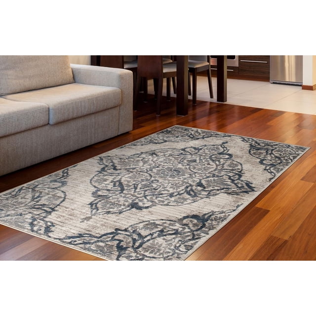 Zunthus Tapis Tissé Beige et Bleu sur Plancher de Bois Franc à Côté d'Un sofa Beige et de Chaises de Salle à Manger en Bois Foncé. Il Présente un Motif vintage Usé avec des Motifs Floraux Bleu Marine et Gris Anthracite et des Losanges sur un Fond Blanc Cassé, Fabriqué avec des Fils de Polypropylène Résistants aux Taches, Idéal pour les Zones à Fort Passage.